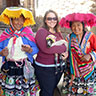Kim holding a lamb and posing with two Andean women in their traditionl clothing