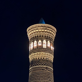 The top of a minaret lit up at night