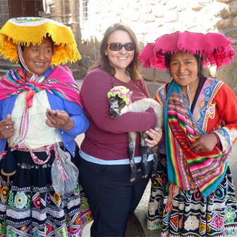 Kim holding a lamb and posing with Andean women