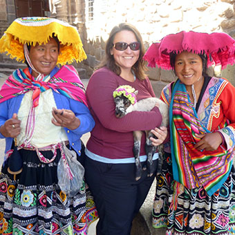 Kim holding a lamb and posing with two Andean women